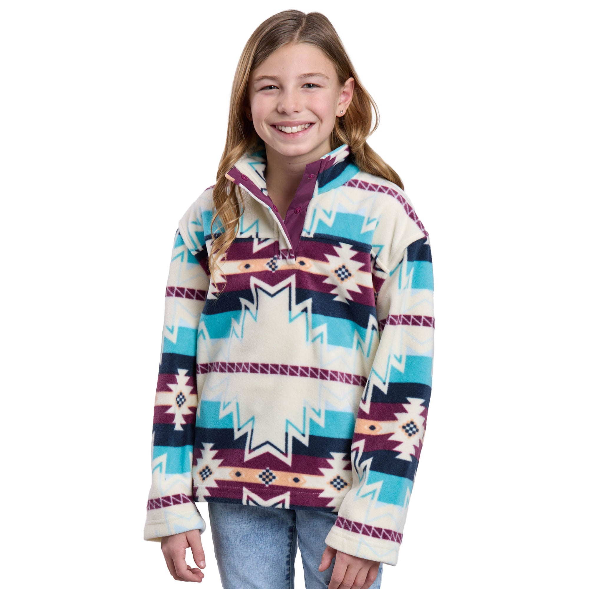 A smiling young girl with long light brown hair wears the Roper Girls L/S Pullover (29250706) Multi, featuring geometric shapes in blue, purple, and cream by Roper, paired with light blue jeans against a white background.