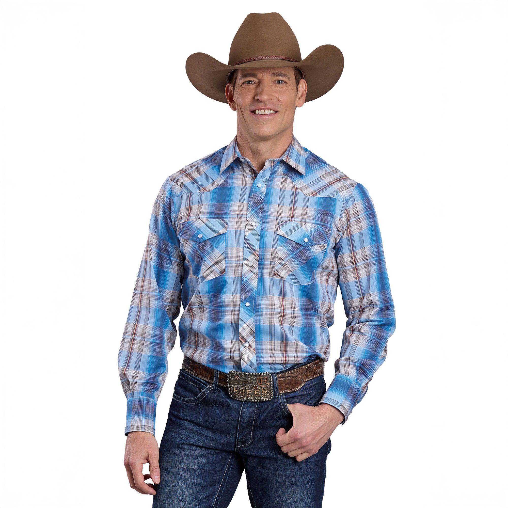 A smiling man wears the Roper Mens Karman Classic 55/45 Collection L/S Shirt (01101220) Plaid Blue, jeans, a brown cowboy hat, and a large belt buckle as he stands against a white background with one hand on his hip.