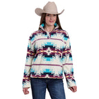 A woman in a beige cowboy hat, blue jeans, and the Roper Womens L/S Pullover (98250706) Multi—featuring teal, burgundy, and white geometric designs—stands smiling at the camera.