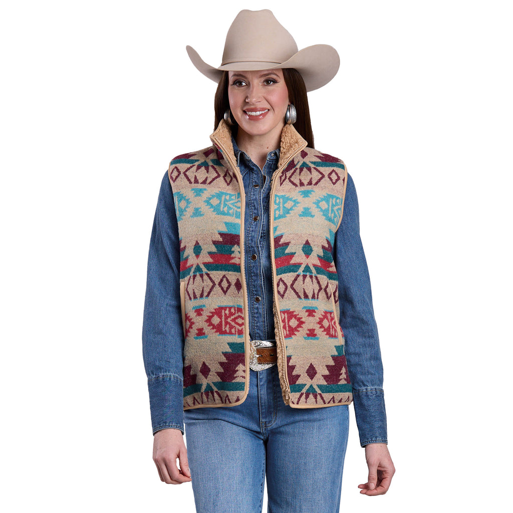 A woman in a beige cowboy hat, denim shirt, large silver earrings, and a Roper Womens Vest (98781127) White with Southwestern designs smiles against a white background.