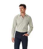 A man wears the R.M.Williams Mens Sommers Poplin Stripe L/S Shirt (SH200PM01) in white and green stripe, standing against a plain white background with one hand in his pocket and looking slightly to the side.