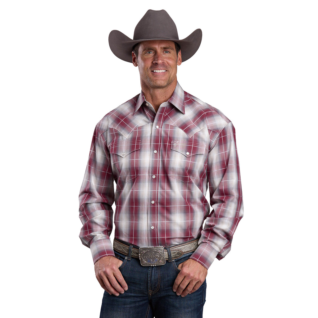 A man in a brown cowboy hat, blue jeans, large belt buckle, and a Stetson Mens Collection L/S Shirt (01478007) Plaid Red by Stetson is smiling with his hands near his waist.