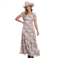 A woman in a Stetson Womens Collection S/S Dress (57590304) Print White and a tan cowboy hat poses smiling with one hand on her waist against a white background.