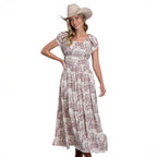 A woman in a Stetson Womens Collection S/S Dress (57590304) Print White and a tan cowboy hat poses smiling with one hand on her waist against a white background.