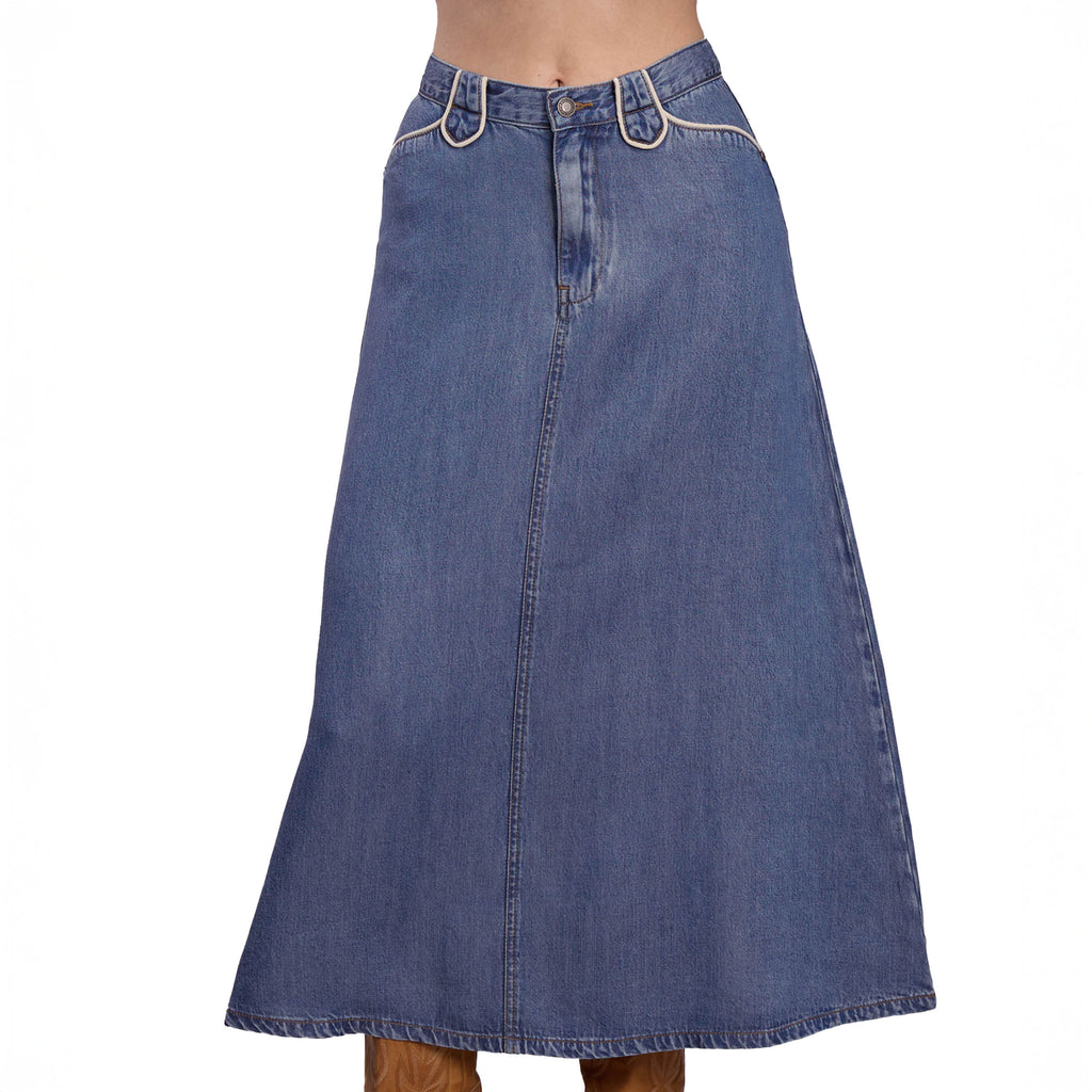 A person wears the Stetson Womens Collection Skirt (60565013), a high-waisted, western A-line blue denim skirt with belt loops, front seams, and brown stitching by Stetson, paired with tan boots. The skirt reaches mid-calf.
