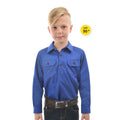 A young boy modelling a cobalt blue Thomas Cook Children's Heavy Drill Half Button Long Sleeve Shirt (TCP7100163) with two chest pockets, paired with dark jeans and a brown belt, on a white background with a yellow 'UPF 50+' badge.