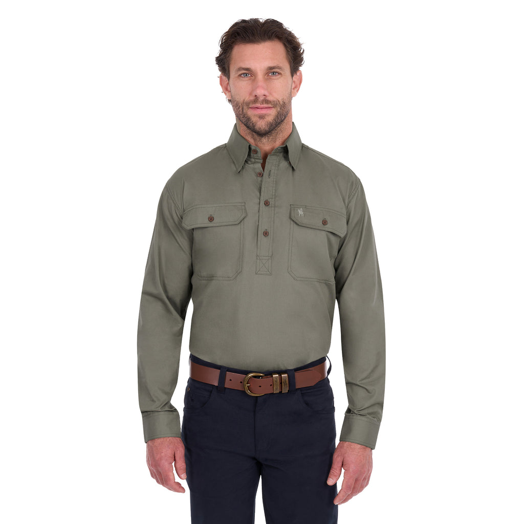 A man modelling a military green Thomas Cook Light Drill Half Button Long Sleeve Work Shirt (TCP1126005) with two chest flap pockets, paired with dark jeans and a brown belt, against a plain white background.