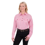 A woman modelling a pale pink Thomas Cook Light Drill Half Button Long Sleeve Work Shirt (TCP1126005) with two chest flap pockets, paired with black jeans and a brown belt, against a plain white background.