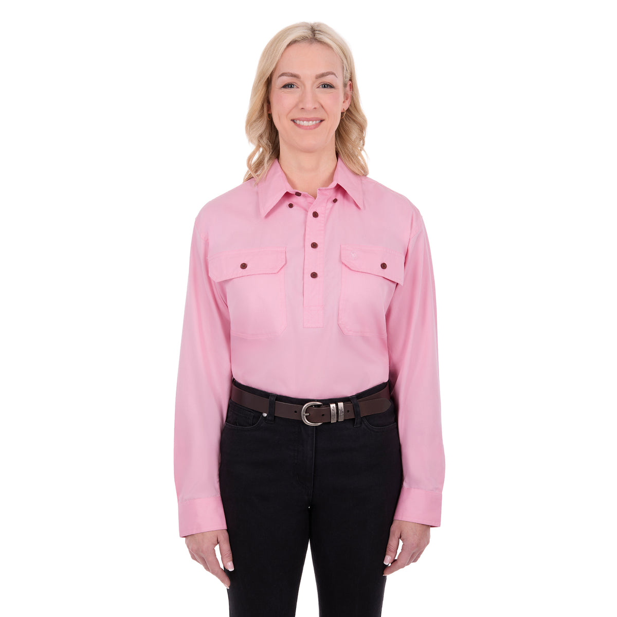 A woman modelling a pale pink Thomas Cook Light Drill Half Button Long Sleeve Work Shirt (TCP1126005) with two chest flap pockets, paired with black jeans and a brown belt, against a plain white background.