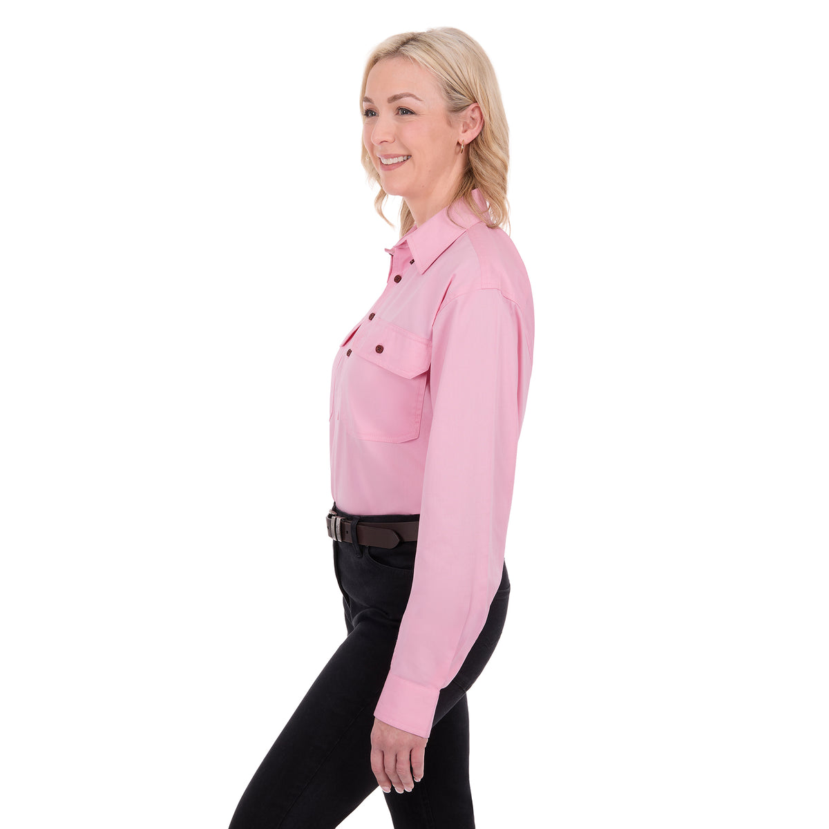 A woman in profile modelling a pale pink Thomas Cook Light Drill Half Button Long Sleeve Work Shirt (TCP1126005) with two chest flap pockets, paired with black jeans and a brown belt, against a plain white background.