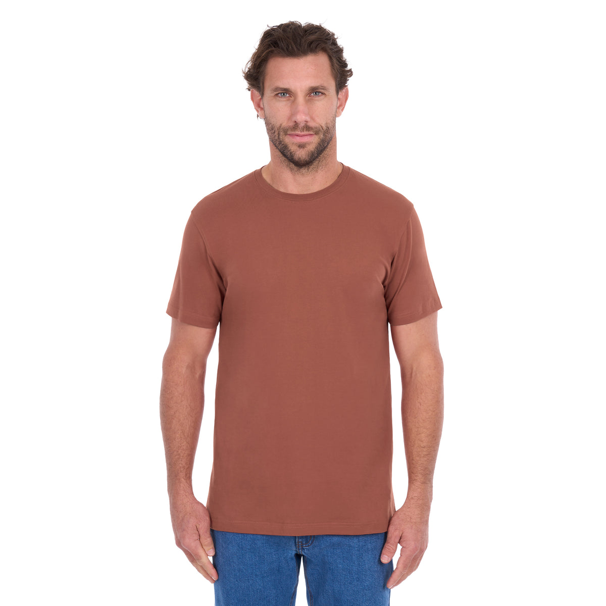 A man modelling a rust Thomas Cook Men's Classic Fit Short Sleeve Tee (TCP1514051) paired with blue denim jeans on a white background.