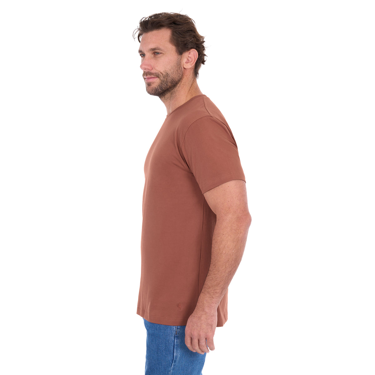 A man in profile modelling a rust Thomas Cook Men's Classic Fit Short Sleeve Tee (TCP1514051) paired with blue denim jeans on a white background.