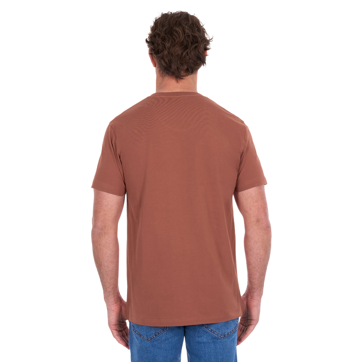 A man viewed from behind modelling a rust Thomas Cook Men's Classic Fit Short Sleeve Tee (TCP1514051) paired with blue denim jeans on a white background.