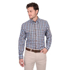 A man wears the Thomas Cook Mens Jonathan L/S Shirt (T6W1115039) Blue/Multi, featuring cotton check fabric and horseman embroidery, along with beige pants and a brown belt, standing against a white background looking to his left.