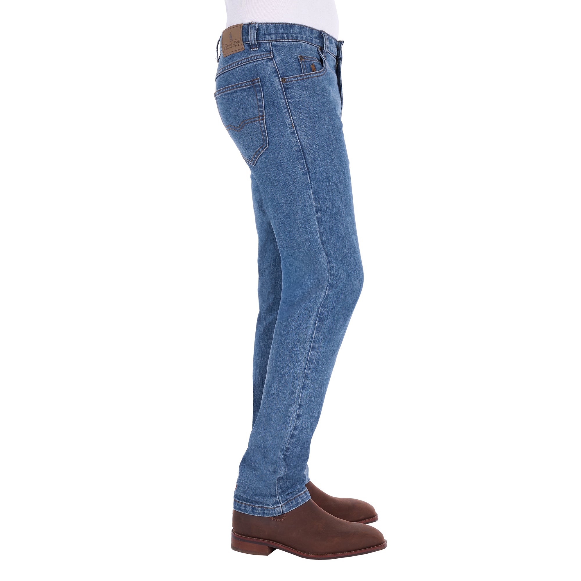 A man shown from the waist down, in profile, modelling a pair light blue Thomas Cook Men's Lochie Tailored Jeans (TCP1226064) paired with brown boots on a white background.