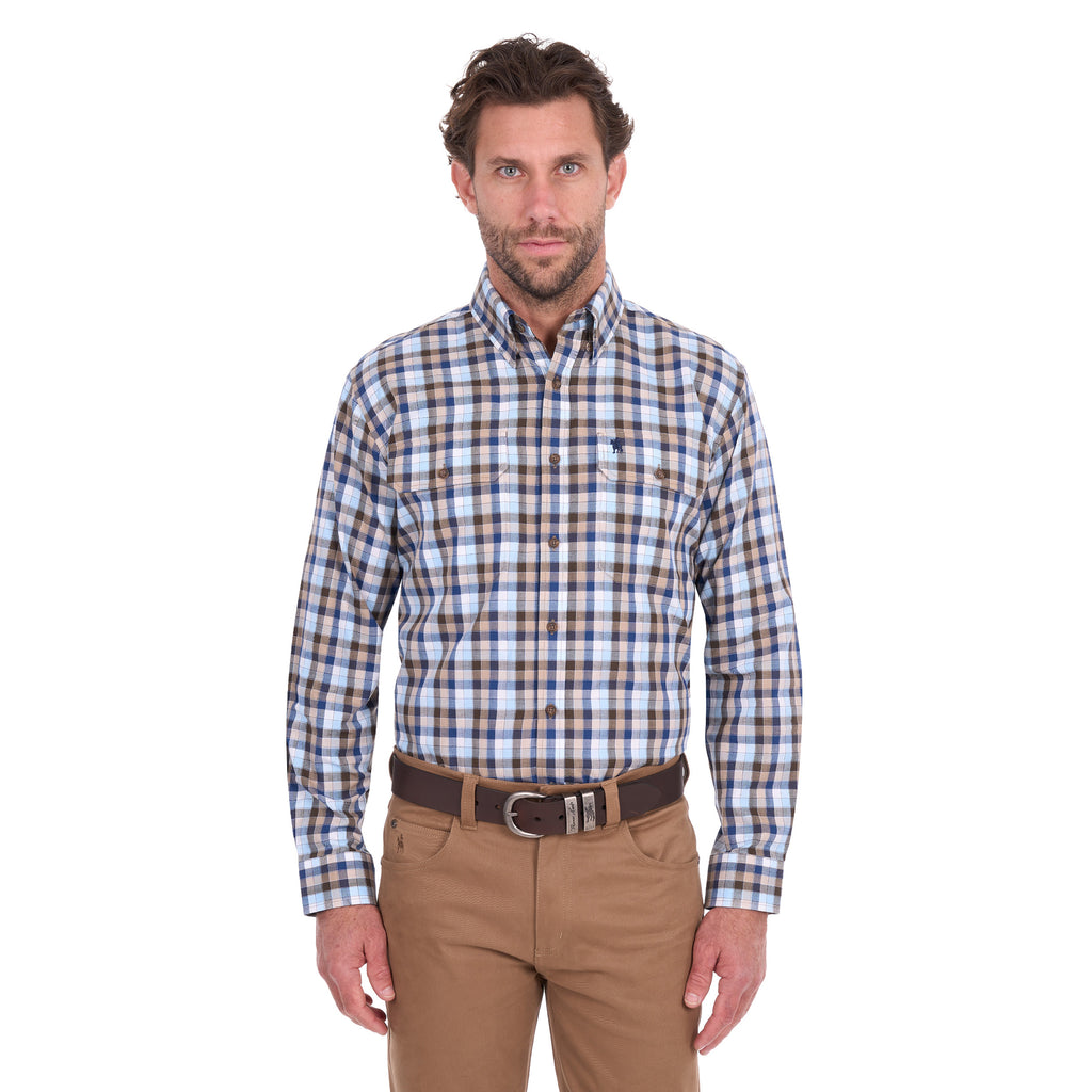 A man modelling a navy, tan, blue and white Thomas Cook Men's Mitchell Long Sleeve Shirt (TCP1115100) paired with a brown belt and camel coloured jeans on a white background.