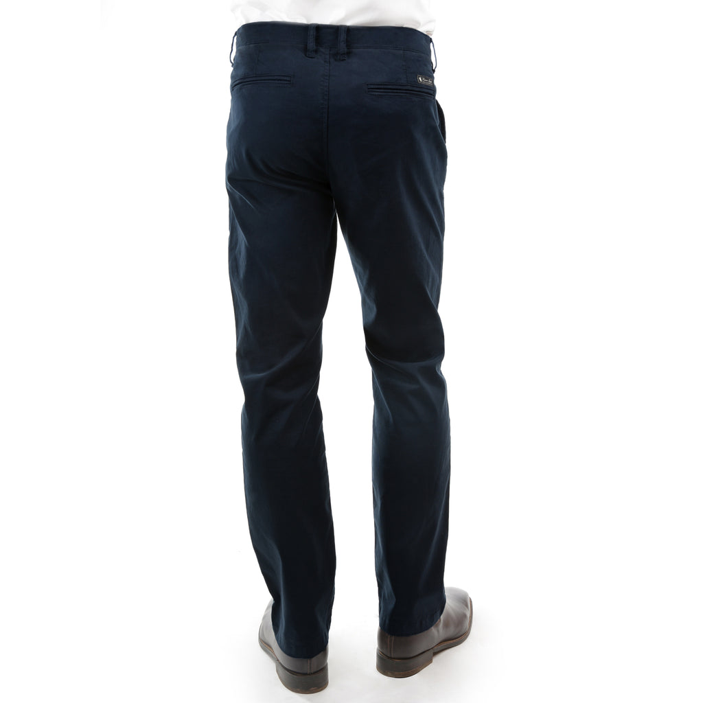 A man viewed from the back, from the waist down wearing a pair of dark navy Thomas Cook Men's Tailored Fit Mossman Comfort Waist Trousers (TCP1209091) with a pair of brown boots on a white studio background.