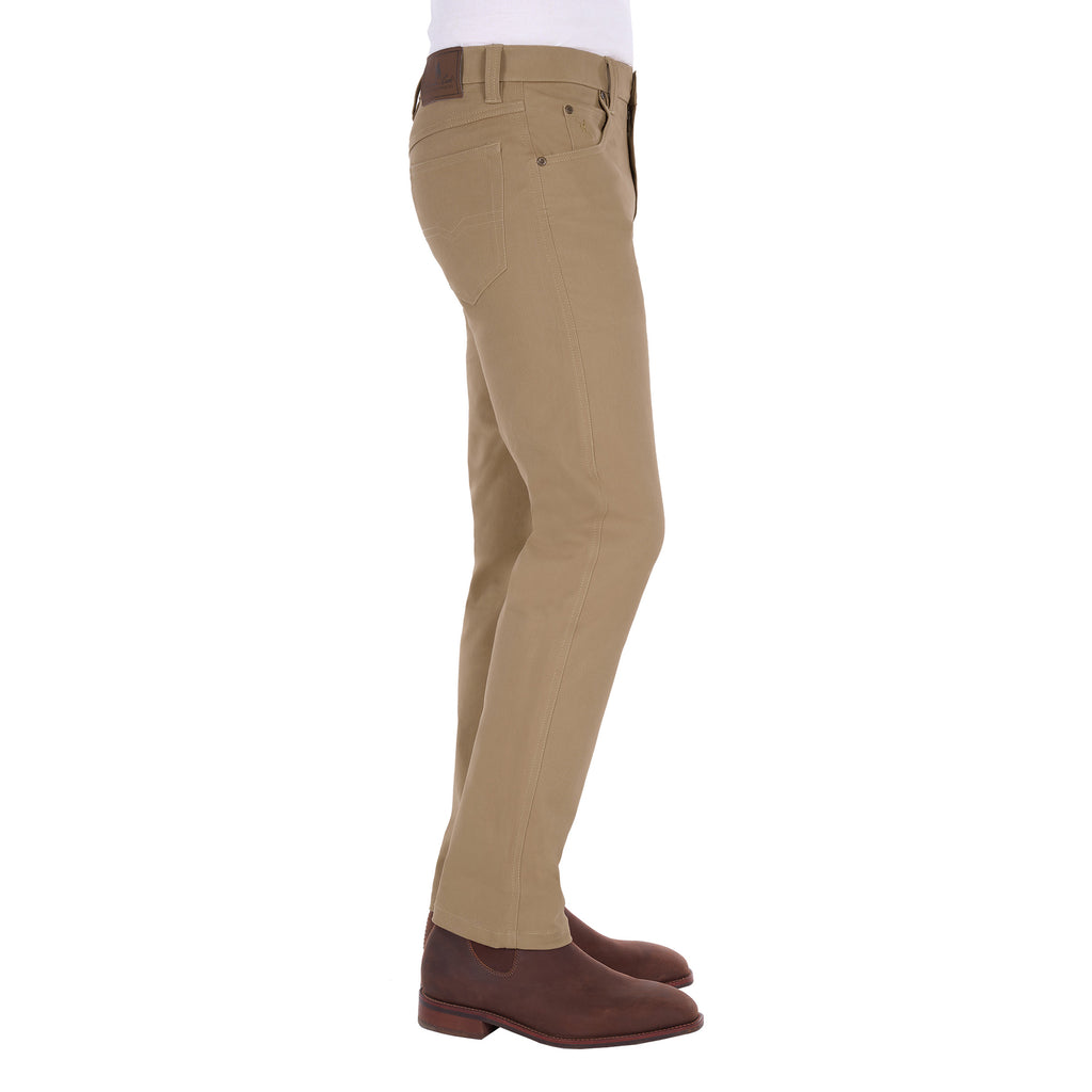 A man in profile from the waist down modelling a pair of sand coloured Thomas Cook Men's Tailored Moleskin Jeans 30" Leg (TCP1206007) paired with a white tee and brown boots.