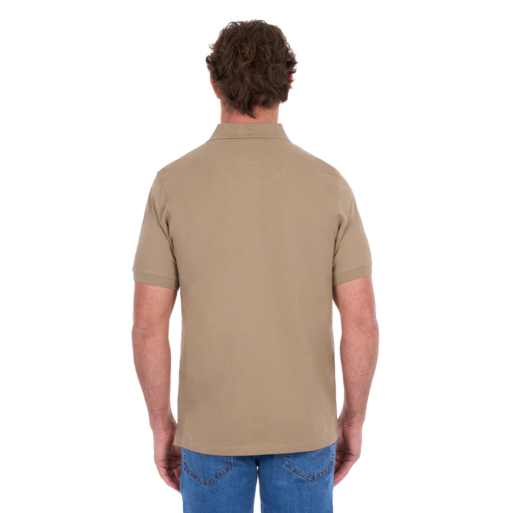 A man shown from behind, modelling a sand coloured Thomas Cook Men's Tailored Short Sleeve Polo (TCP1506009) paired with blue denim jeans on a white background.
