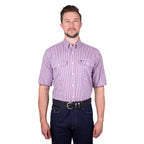 A man wearing a royal blue, white and red Thomas Cook Men's Wentworth Short Sleeve Dress Shirt (TCP1110158) with two chest pockets, paired with dark blue jeans and a black belt, against a plain white background.