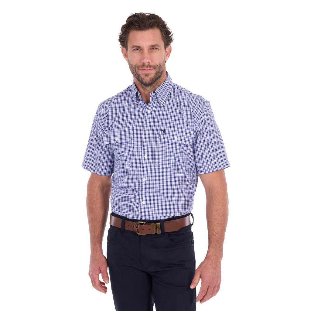 A man modelling a navy blue and white Thomas Cook Men's Wentworth Short Sleeve Check Shirt (TCP1110158) with navy blue pants and a brown belt.