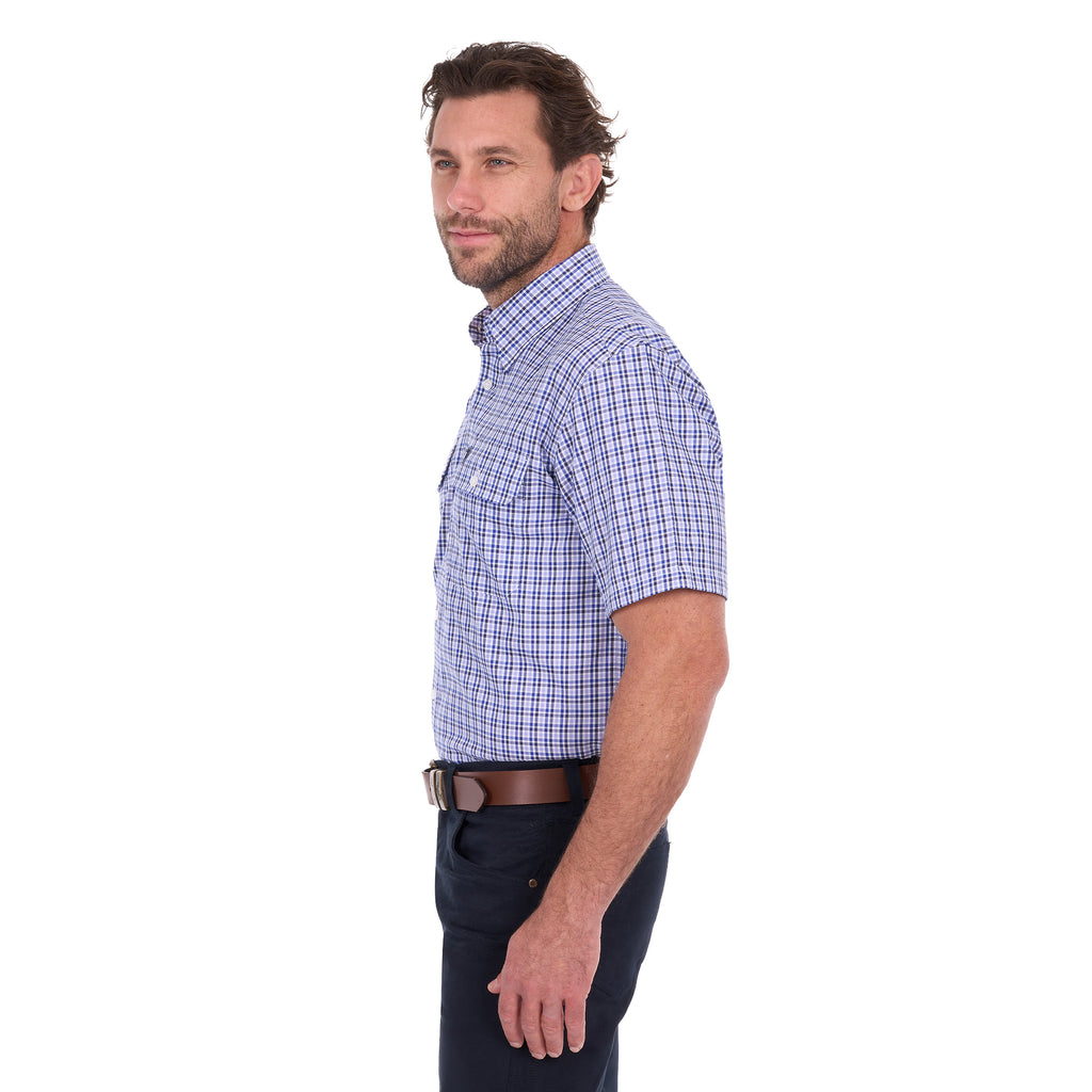 A man in profile modelling a navy blue and white Thomas Cook Men's Wentworth Short Sleeve Check Shirt (TCP1110158) with navy blue pants and a brown belt.