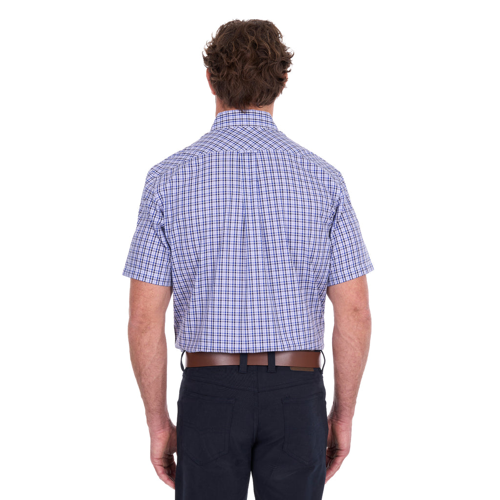 A man viewed from behind modelling a navy blue and white Thomas Cook Men's Wentworth Short Sleeve Check Shirt (TCP1110158) with navy blue pants and a brown belt.