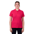 A woman modelling a bright rose coloured Thomas Cook Women's Classic Stretch Short Sleeve Polo Shirt (TCP2512059) with a small navy embroidered logo on the left chest, set against a plain white background.