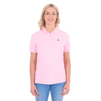 A woman modelling a light pink Thomas Cook Women's Classic Stretch Short Sleeve Polo (TCP2512059) and blue jeans, against a plain white background.