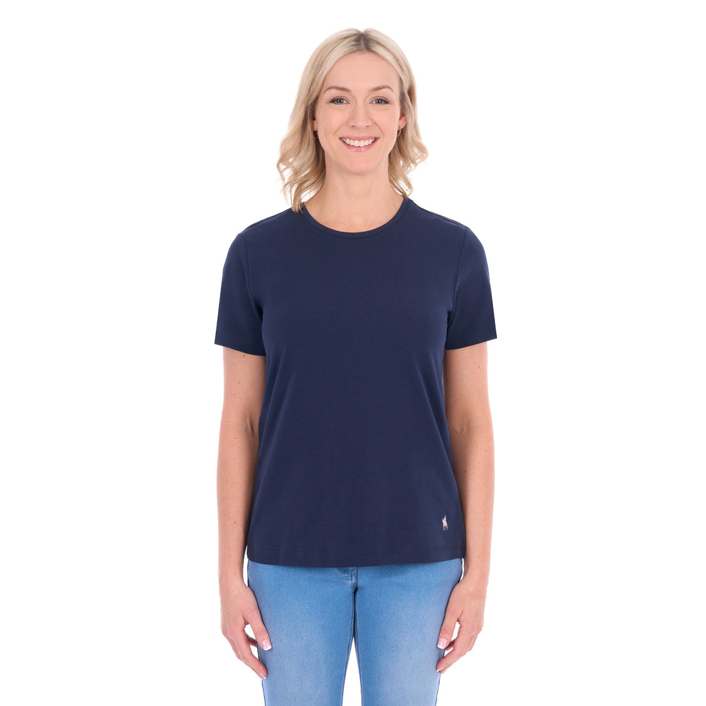 A woman modelling a navy blue Thomas Cook Women's Round Neck Short Sleeve Tee (TCP2515104) paired with blue denim jeans on a white background.