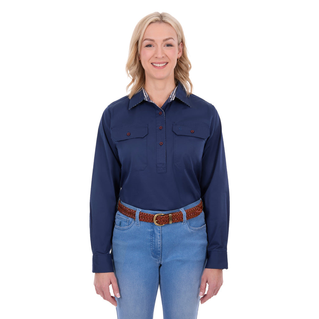 A woman modelling a navy blue Thomas Cook Women's Stretch Drill Half Button Long Sleeve Work Shirt (TCP2100106) with two chest pockets, paired with blue jeans and a brown woven belt, against a plain white background.