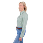 A woman in profile modelling a mint green Thomas Cook Women's Stretch Drill Half Button Long Sleeve Work Shirt (TCP2100106) with two chest pockets, paired with blue jeans and a brown woven belt, against a plain white background.