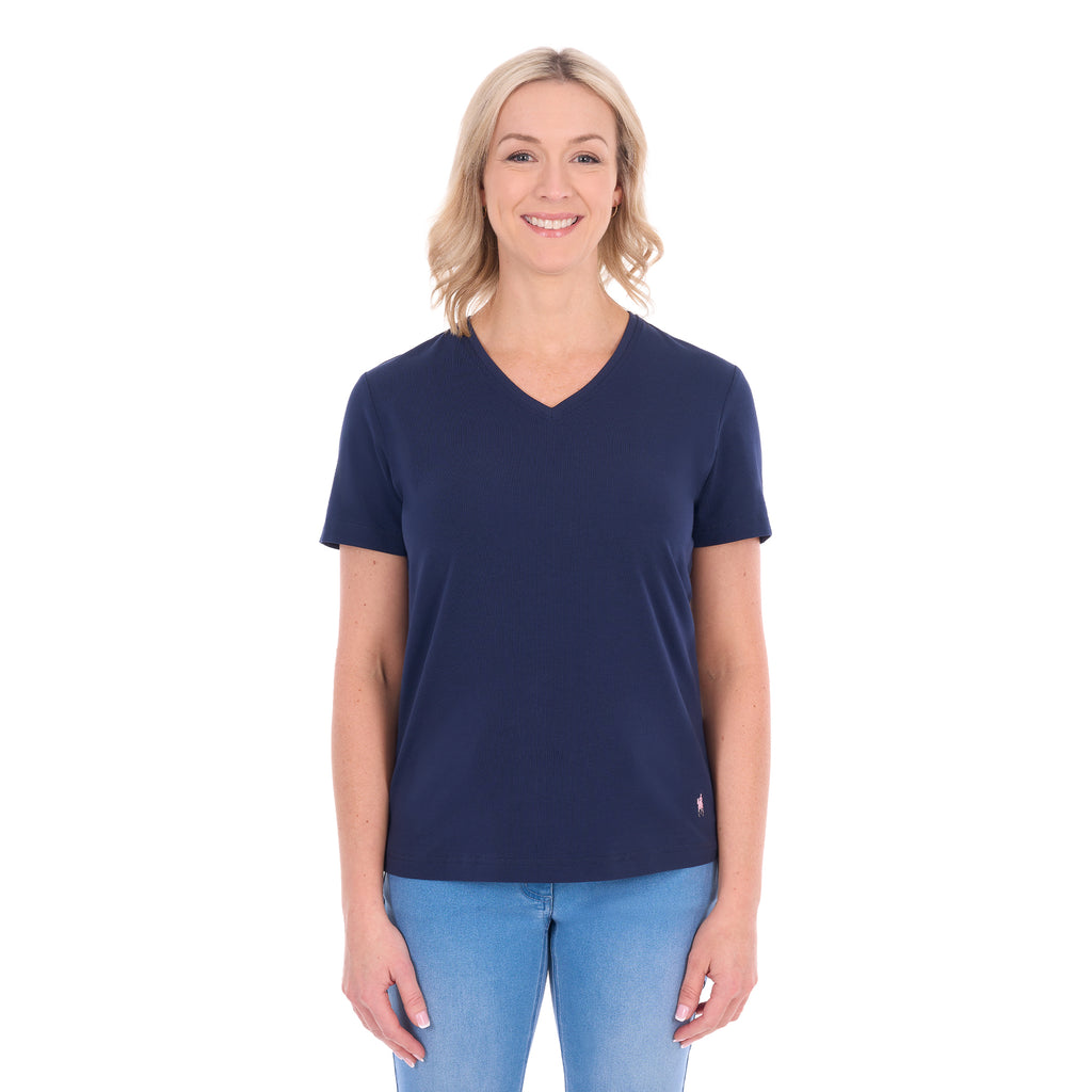 A woman with blonde hair wearing a navy blue Thomas Cook Women's V Neck Short Sleeve Tee (TCP2550105) and denim jeans, standing against a plain white background.