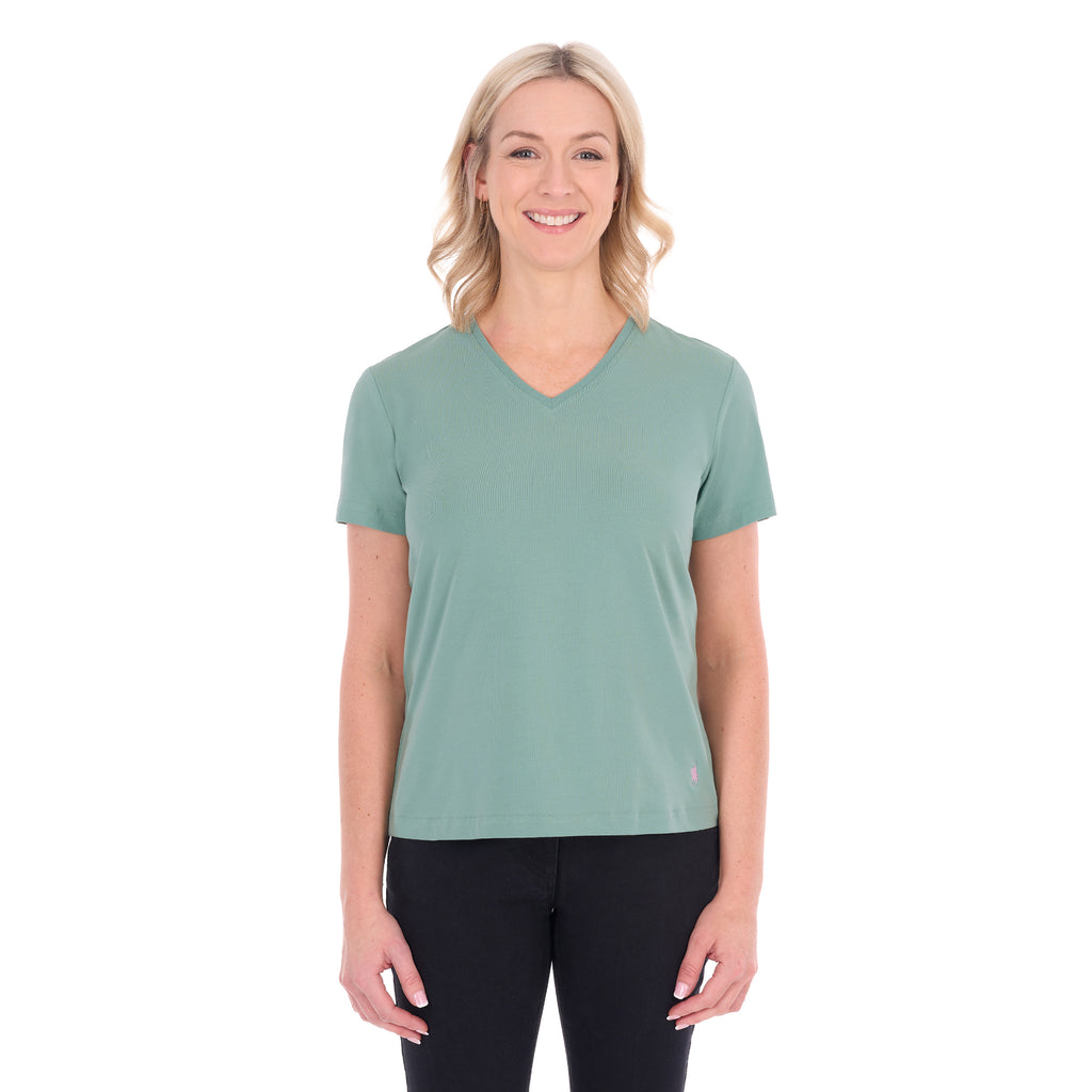 A woman with blonde hair wearing a sage green Thomas Cook Women's V Neck Short Sleeve Tee (TCP2550105) and black pants, standing against a plain white background.
