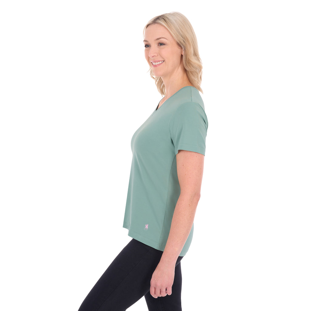 A woman in profile with blonde hair wearing a sage green Thomas Cook Women's V Neck Short Sleeve Tee (TCP2550105) and black pants, standing against a plain white background.