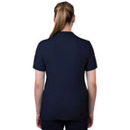 A woman viewed from behind wearing a navy blue Thomas Cook Women's Classic Stretch Short Sleeve Polo with a Thomas Cook embroidered logo on a white background.