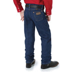 A boy shown from behind, from the waist down wearing a pair of prewashed indigo Wrangler Boys Junior Original ProRodeo Regular Fit Jeans (13MWZJPREG) paired with western boots, a western belt and a red shirt on a white background.
