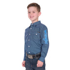 A smiling boy wears the Wrangler Boys Kyle Logo L/S Shirt (X6W3111481) in navy/blue with "Wrangler" on the sleeve, paired with blue jeans and a large belt buckle, standing against a white background.