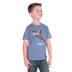 A young boy wearing a storm blue Wrangler Boys Michael Short Sleeve Tee (X6S3557684) with a cowboy graphic print, paired with blue jeans, standing against a solid white background.