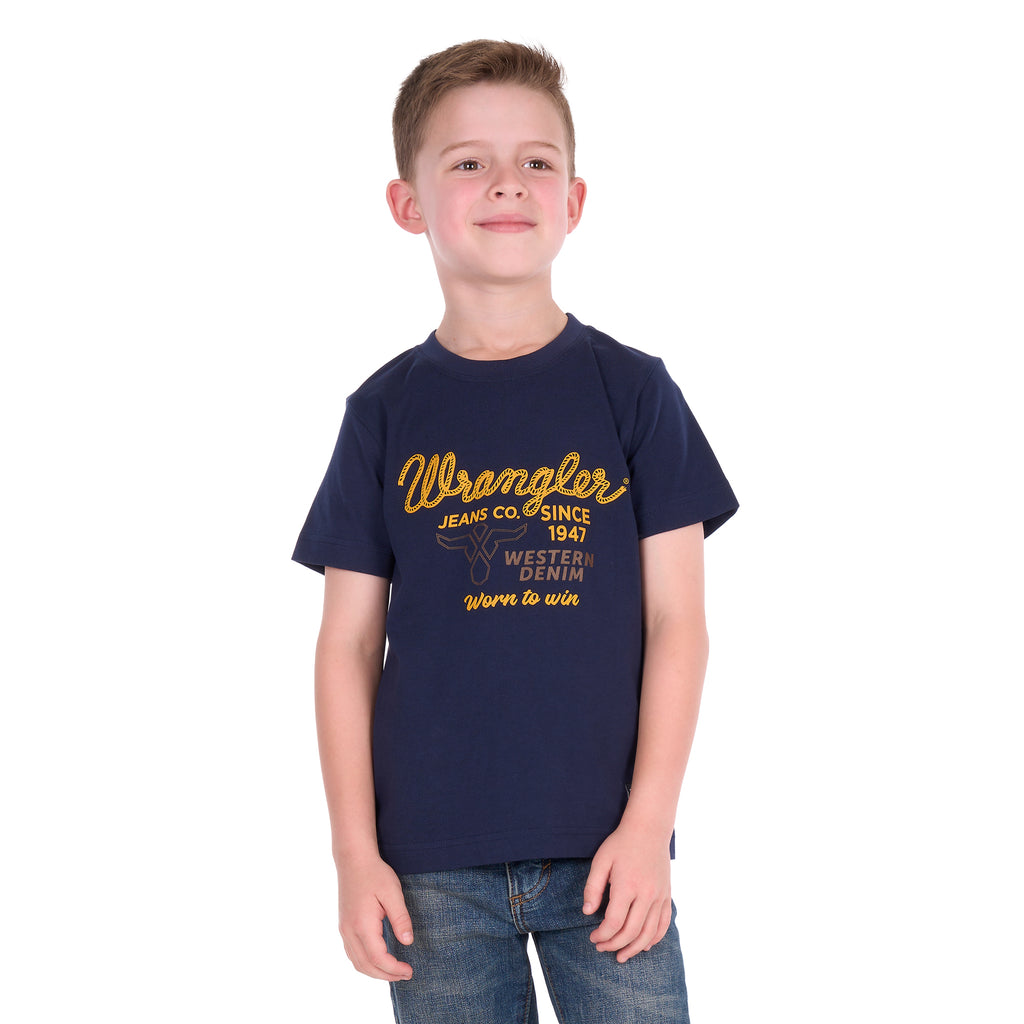 A young boy facing the camera wearing a Wrangler Boys Robert Short Sleeved Tee (X6S3557687) in Navy with a pair of denim jeans.