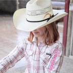 A child wearing a natural Wrangler Children's Boll Bangora Hat (X4Y3901BOL) with a black band and a pink plaid shirt, photographed in a rustic outdoor setting.