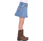 A girl in profile wearing a faded blue Wrangler Girls Grace Skirt (X6S5202720) with decorative stitching and brown cowboy boots, against a plain white background.