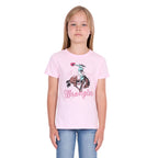 A young girl with blonde hair wearing a pastel pink Wrangler Girls Jenna T-Shirt (X6S5598639) with a cowboy graphic and blue jeans, standing against a plain white background.