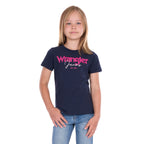 A young girl with blonde hair wearing a navy blue Wrangler Girls Maya T-Shirt (X6S5598649) and blue jeans, standing against a plain white background.