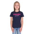 A young girl with blonde hair wearing a navy blue Wrangler Girls Maya T-Shirt (X6S5598649) and blue jeans, standing against a plain white background.