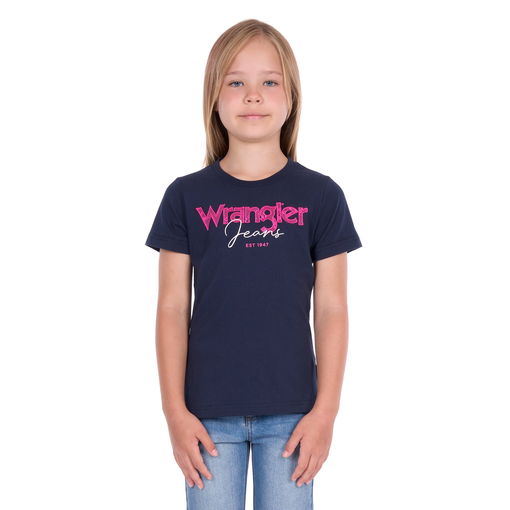 A young girl with blonde hair wearing a navy blue Wrangler Girls Maya T-Shirt (X6S5598649) and blue jeans, standing against a plain white background.