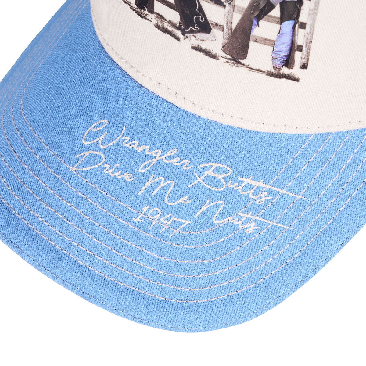 A light blue and cream Wrangler Josie High Profile Trucker Cap (X6S2943CAP) featuring a western-themed graphic print on the front panel and cream embroidered text on the brim.