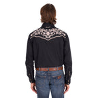 A man wearing a black Wrangler Men's Anthony Embroidered L/S Shirt (X6S1113674) Black with intricate white floral embroidery across the back, paired with blue jeans and a brown belt, against a plain white background.