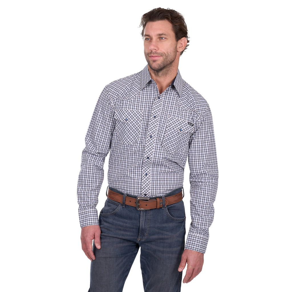 A man wearing a Wrangler Men’s Carl L/S Shirt (X6W1111486) in navy/tan plaid stands against a white background, paired with blue jeans and a brown belt, looking slightly to the side with a relaxed posture.