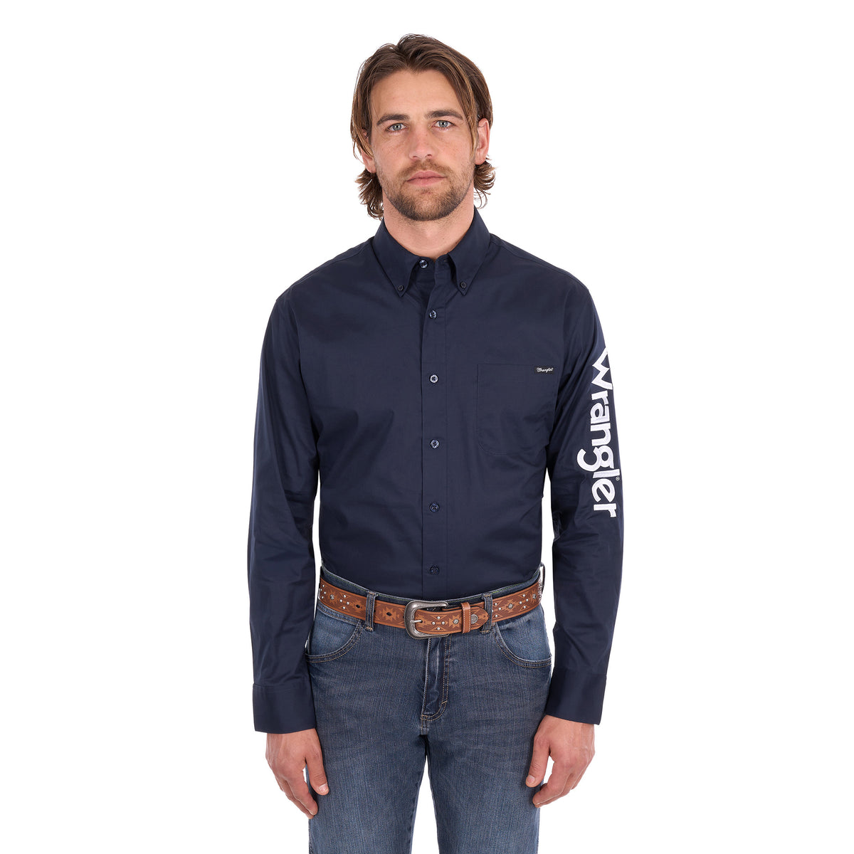 A man wearing a navy blue Wrangler Men's Flex Logo Long Sleeve Shirt (XCP1155359) with a white logo printed vertically on the left sleeve, paired with blue jeans and a Wrangler Onyx Belt (X6S1969BLT), against a plain white background.